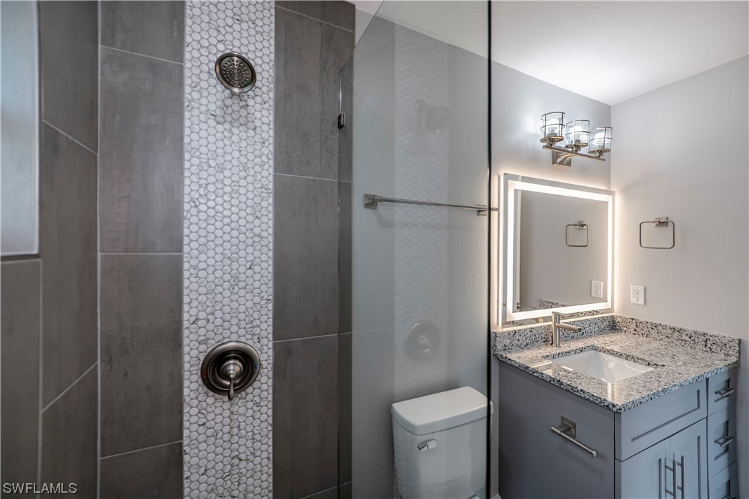 9035 West Crow Circle LaBelle, FL 33935 - Photo 23 of 32 a bathroom with a granite countertop sink a toilet and shower