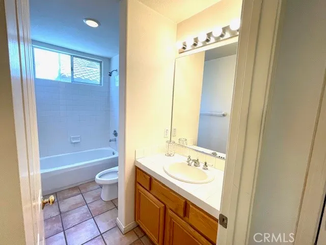 a bathroom with a granite countertop sink a toilet a mirror and bathtub
