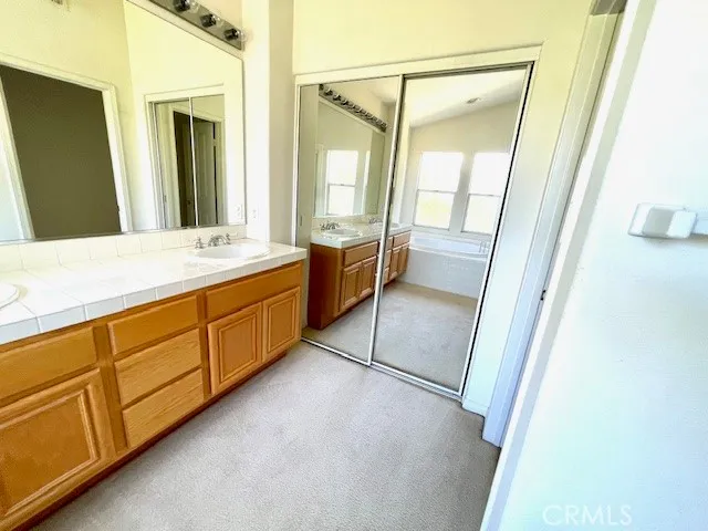 a spacious bathroom with a double vanity sink a mirror and a bathtub