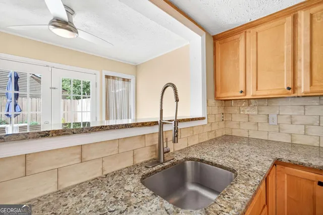 a kitchen with granite countertop a sink a stove and cabinets