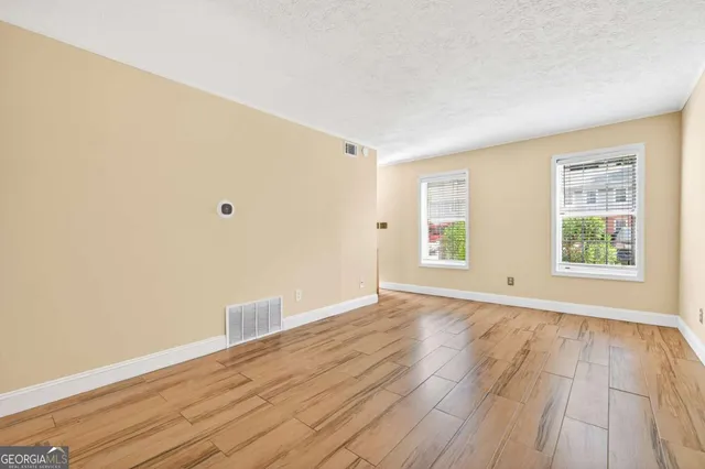 an empty room with wooden floor and windows