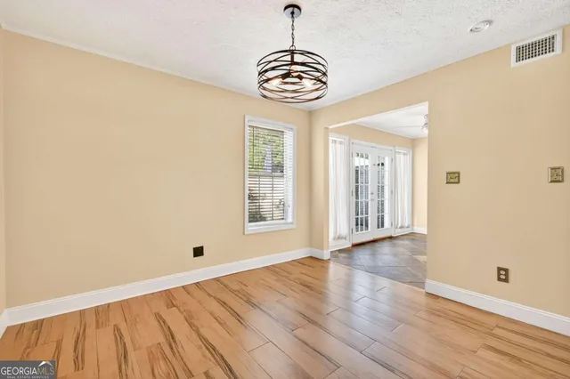 a view of an empty room with window and wooden floor