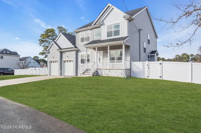 a view of a white house next to a yard with potted plants