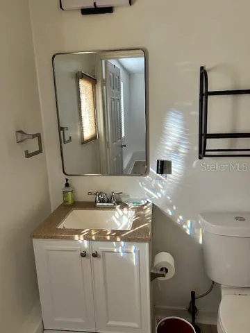 a bathroom with a granite countertop sink a toilet mirror and vanity