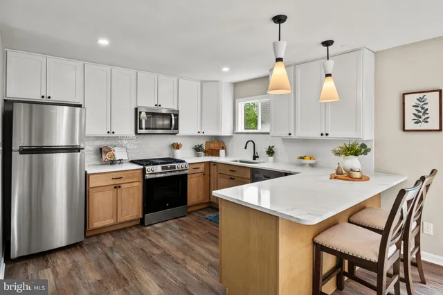 a kitchen with stainless steel appliances granite countertop a refrigerator a stove top oven a sink dishwasher and a refrigerator with wooden floor