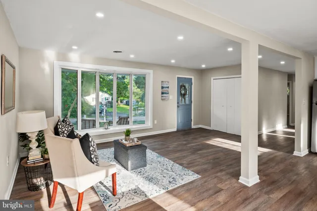 a kitchen with stainless steel appliances a dining table chairs and couches with wooden floor