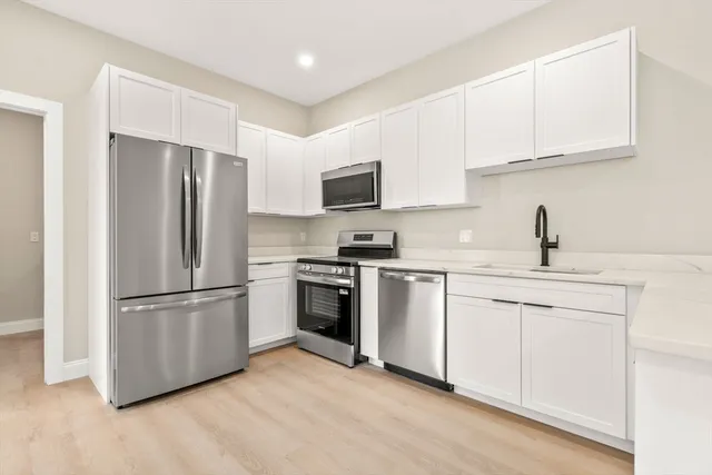 a kitchen with stainless steel appliances white cabinets and a refrigerator