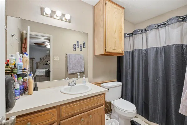 a bathroom with a sink a toilet a mirror and shower curtain