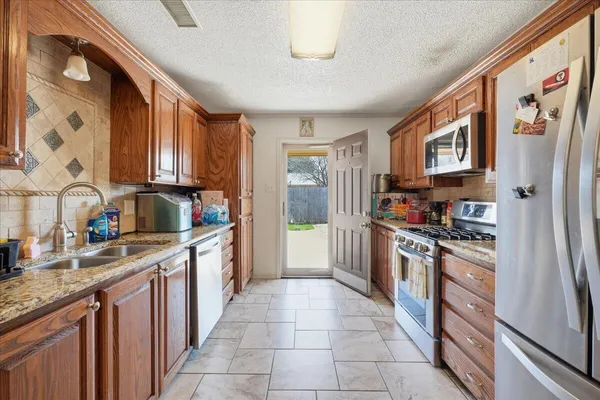 a kitchen with stainless steel appliances granite countertop a refrigerator and a stove top oven