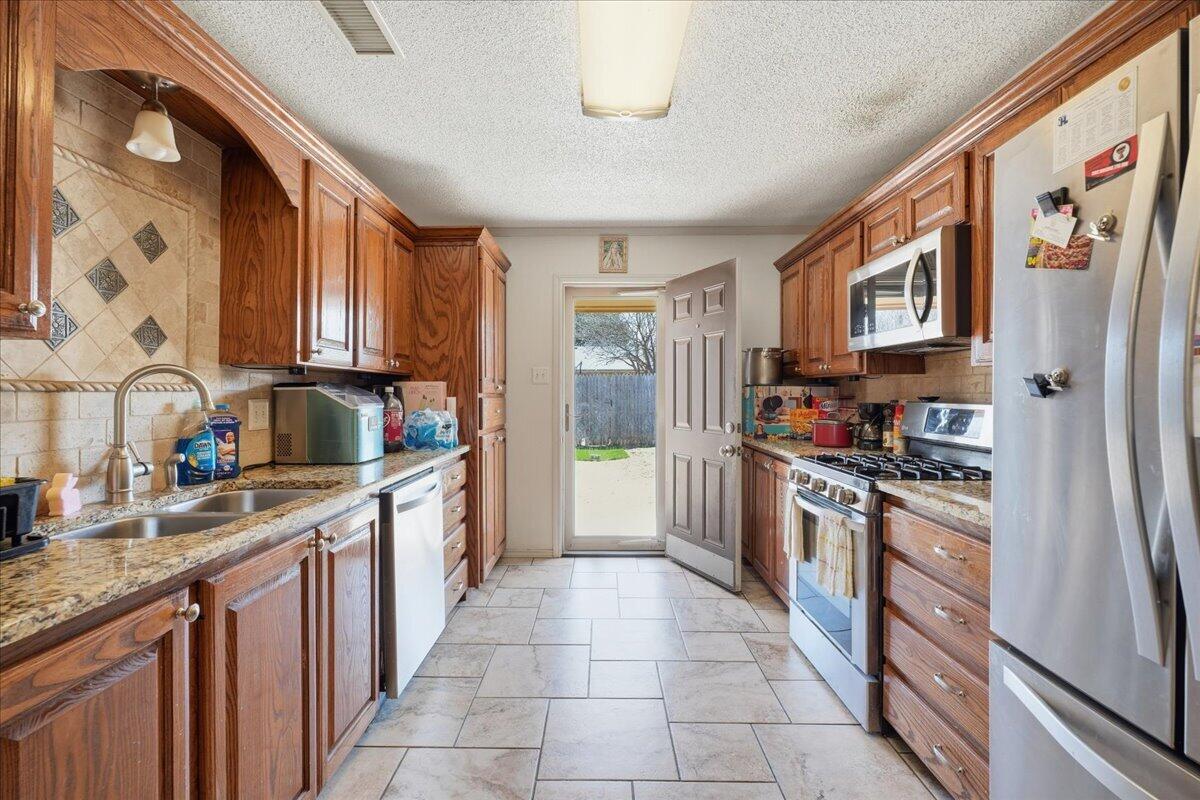 2101 76th Street Lubbock, TX 79423 - Photo 7 of 20 a kitchen with stainless steel appliances granite countertop a refrigerator and a stove top oven