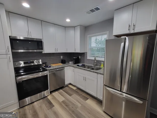 a kitchen with granite countertop a refrigerator stove and microwave