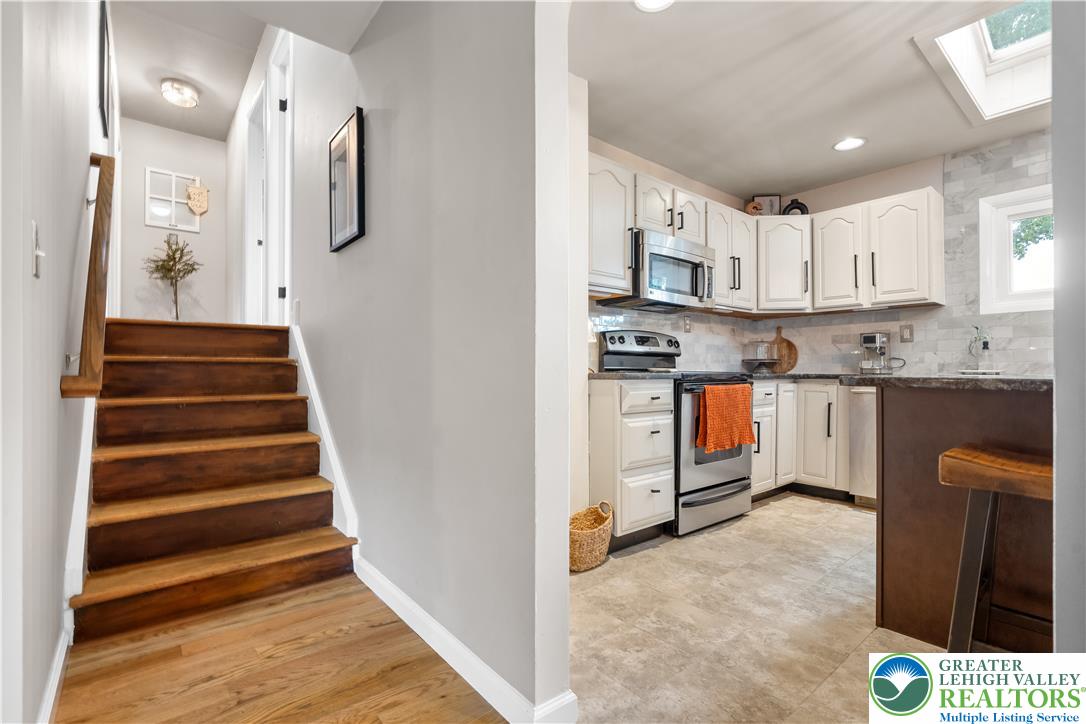 2569 Woods Edge Road Bath, PA 18014 - Photo 20 of 40 An inviting entryway transitions smoothly into a modern kitchen, highlighting rich wood stairs and sleek cabinetry.
