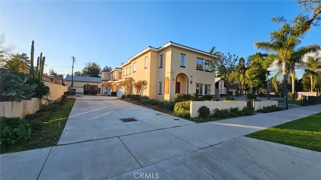 a view of a white house with a small yard and a large tree