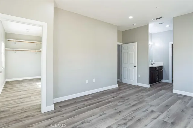 a view of an empty room with wooden floor and closet
