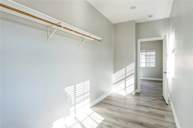 a view of empty room with wooden floor and fan