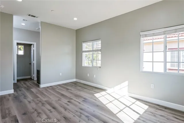 an empty room with wooden floor and windows