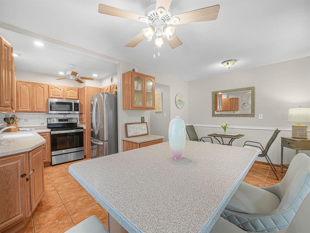 549 Sutton Place, Unit T 19 Longboat Key, FL 34228 - Photo 10 of 52 a kitchen with stainless steel appliances kitchen island granite countertop a refrigerator a stove top oven a sink with island and chairs