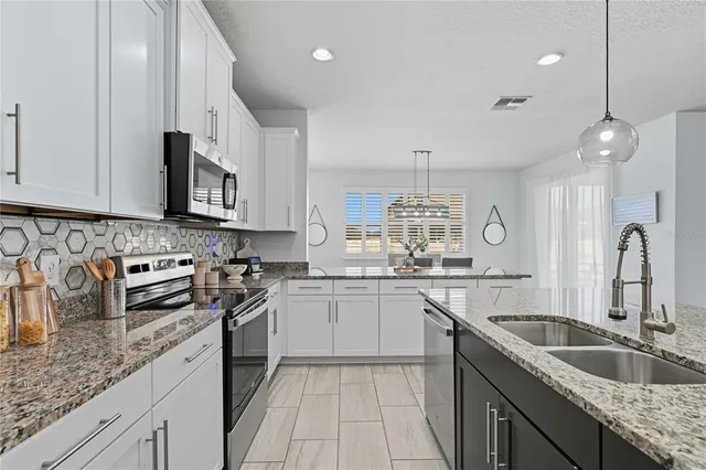 a kitchen with stainless steel appliances granite countertop a sink stove and cabinets
