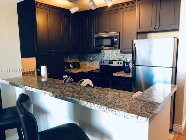 a kitchen with granite countertop a sink a stove and a wooden cabinets