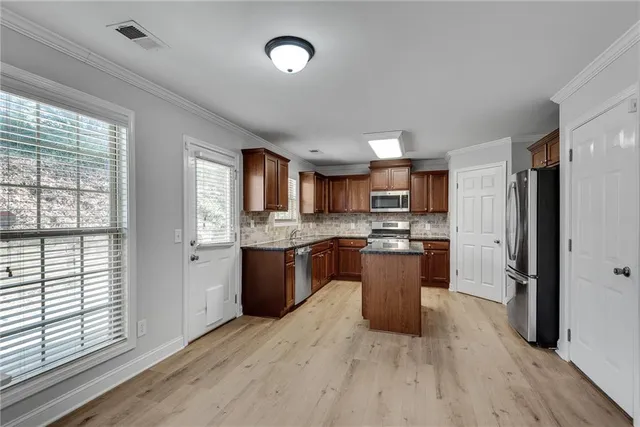 a kitchen with stainless steel appliances granite countertop wooden cabinets a stove a sink and a refrigerator