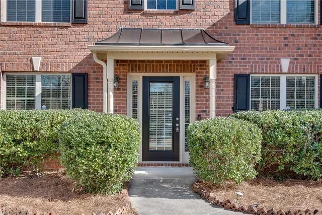 front view of a brick house with potted plants