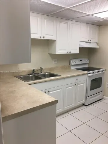 a kitchen with granite countertop a sink a stove and cabinets