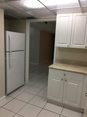 a view of a refrigerator in kitchen and white cabinets