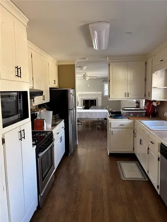 a kitchen with stainless steel appliances a stove top oven a sink dishwasher and a refrigerator with wooden floor