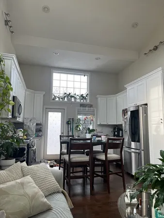a kitchen with stainless steel appliances a dining table chairs refrigerator and sink
