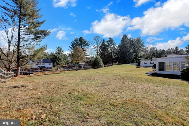 a view of a white house with a fountain plants and large trees