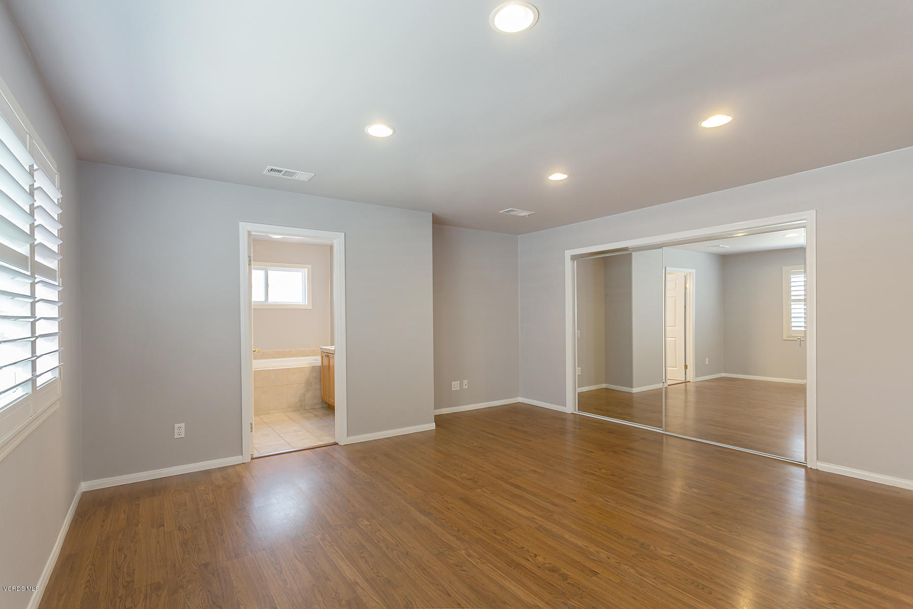 931 Walnut Canyon Road Moorpark, CA 93021 - Photo 11 of 27 an empty room with wooden floor and windows with curtains