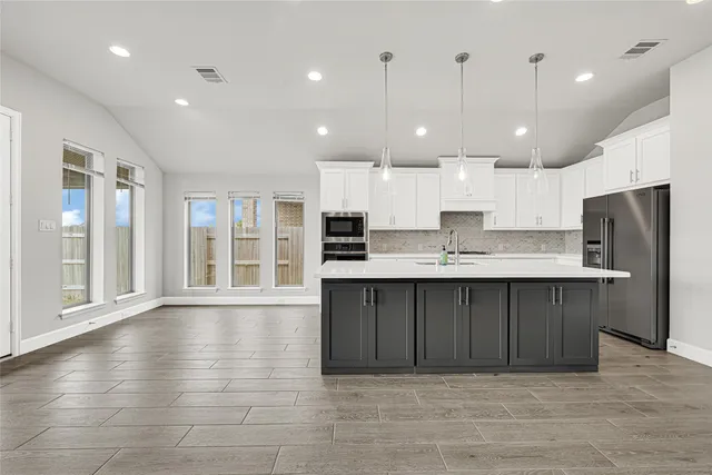 a large kitchen with stainless steel appliances granite countertop a large counter top a refrigerator and a sink