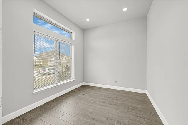 an empty room with wooden floor and windows