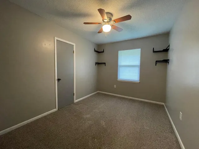 an empty room with a ceiling fan and a window