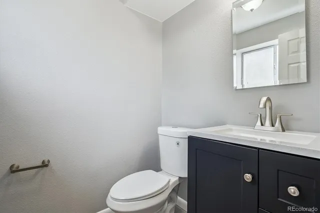a bathroom with a granite countertop toilet sink a mirror and vanity
