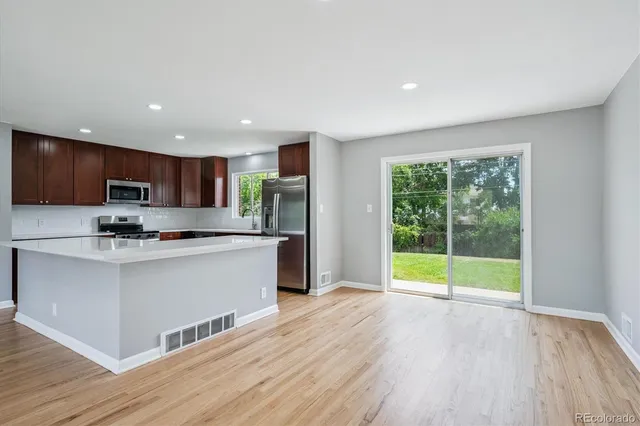 a kitchen with stainless steel appliances granite countertop a refrigerator a sink dishwasher a stove and a wooden floors