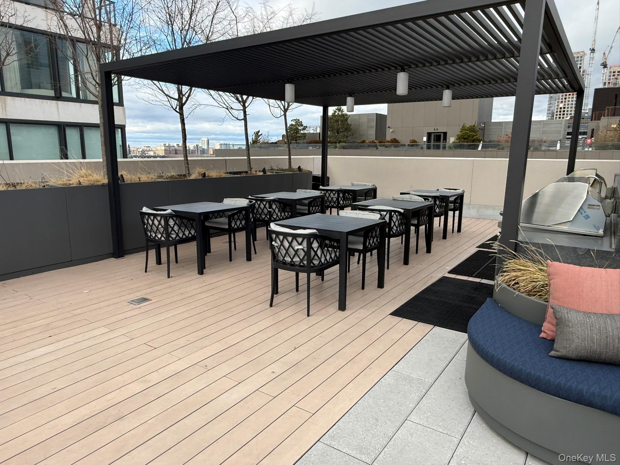 450 Washington Street, Unit 306 Manhattan, NY 10013 - Photo 18 of 33 a view of a roof deck with table and chairs under an umbrella with barbeque grill and wooden floor