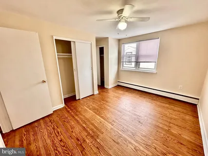 an empty room with wooden floor ceiling fan and windows