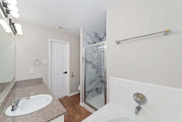 a bathroom with a granite countertop sink a toilet and shower