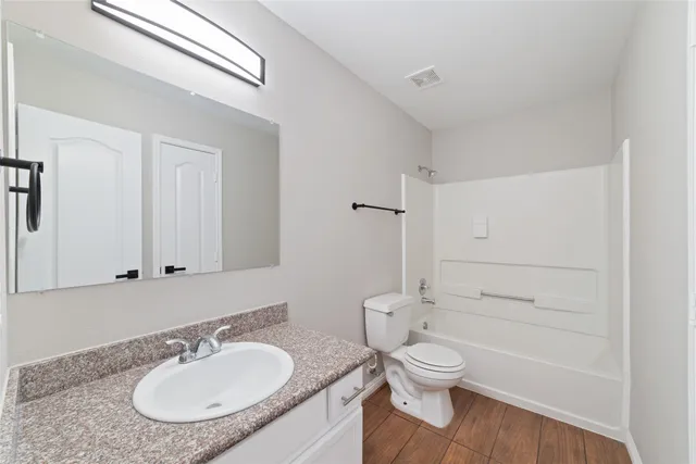 a bathroom with a granite countertop sink toilet a mirror and shower