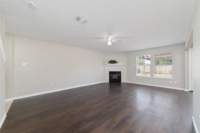 an empty room with wooden floor fireplace and windows