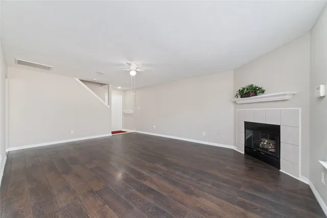 a view of an empty room with wooden floor fireplace and a window