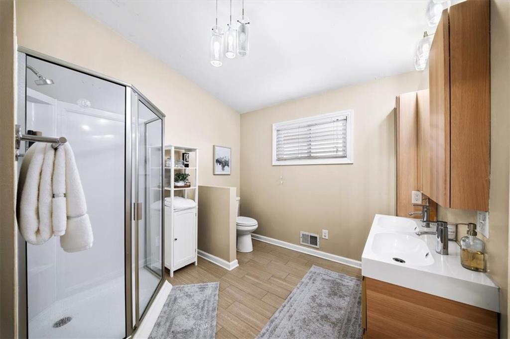 109 Spruell Springs Road Atlanta, GA 30342 - Photo 14 of 34 a spacious bathroom with a double vanity sink a mirror and a shower