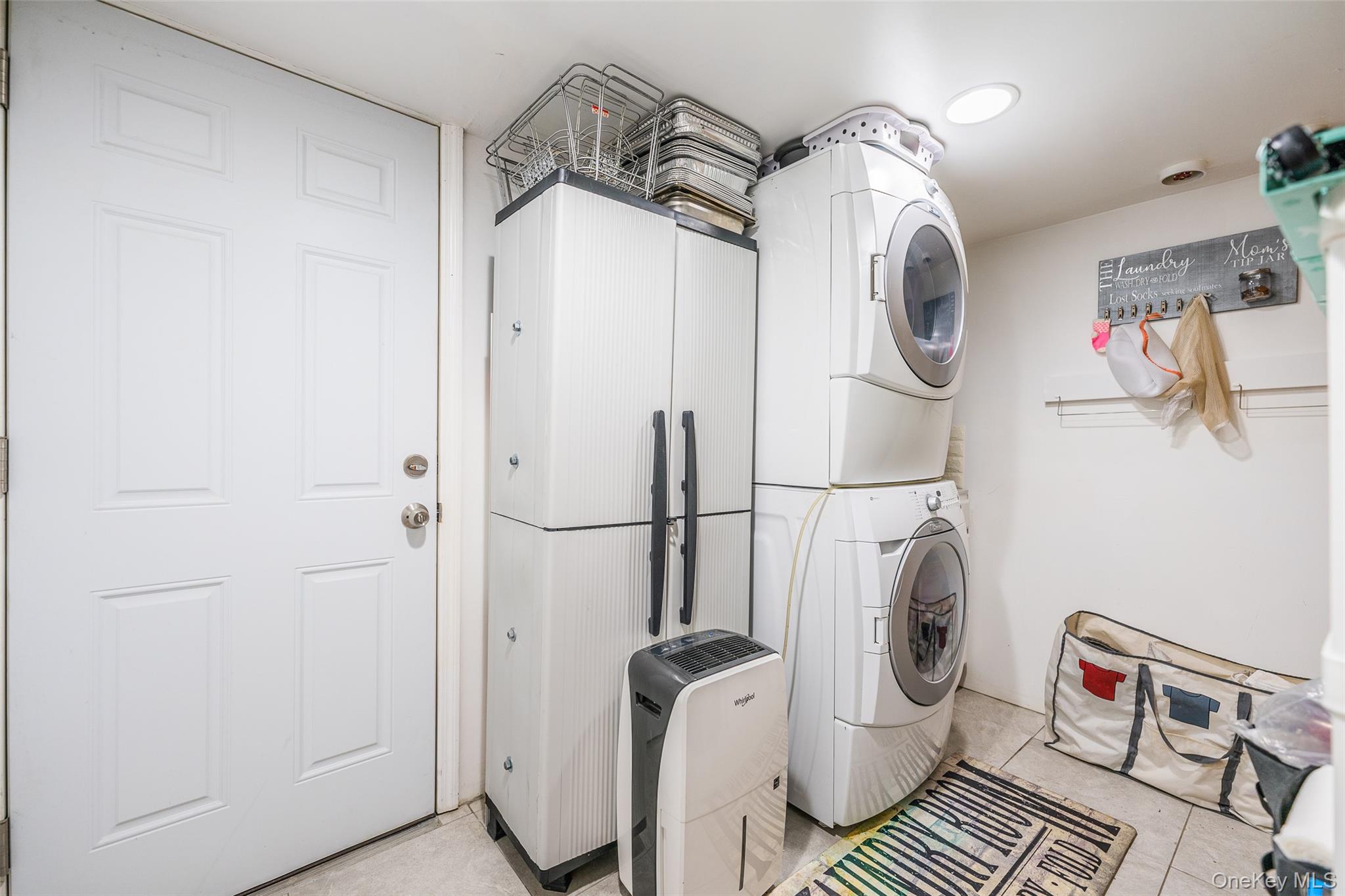 89-32 90th Street Queens, NY 11421 - Photo 17 of 33 Laundry area featuring stacked washer / drying machine and light tile patterned flooring