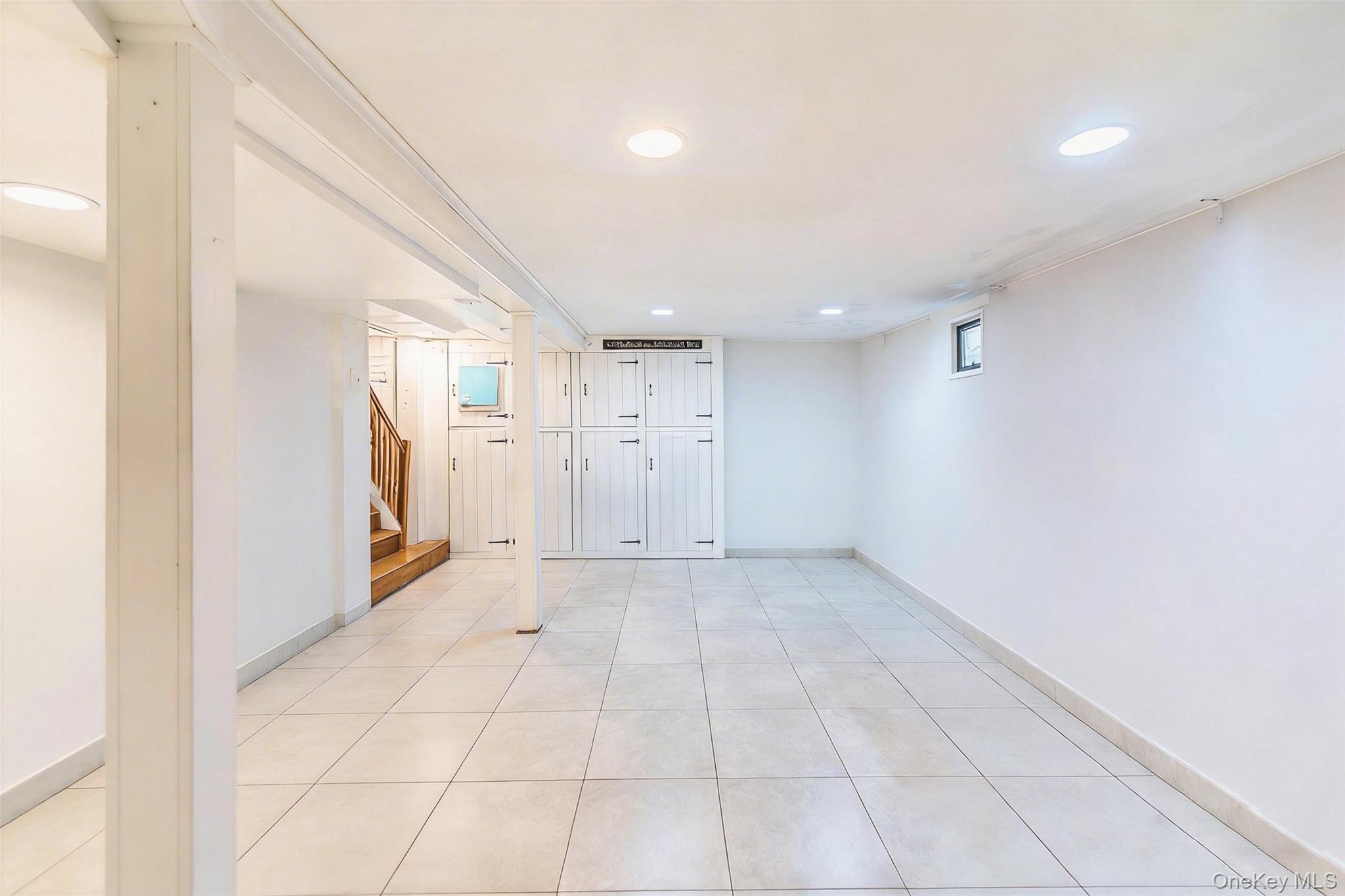 89-32 90th Street Queens, NY 11421 - Photo 18 of 33 Finished basement with light tile patterned flooring and recessed lighting