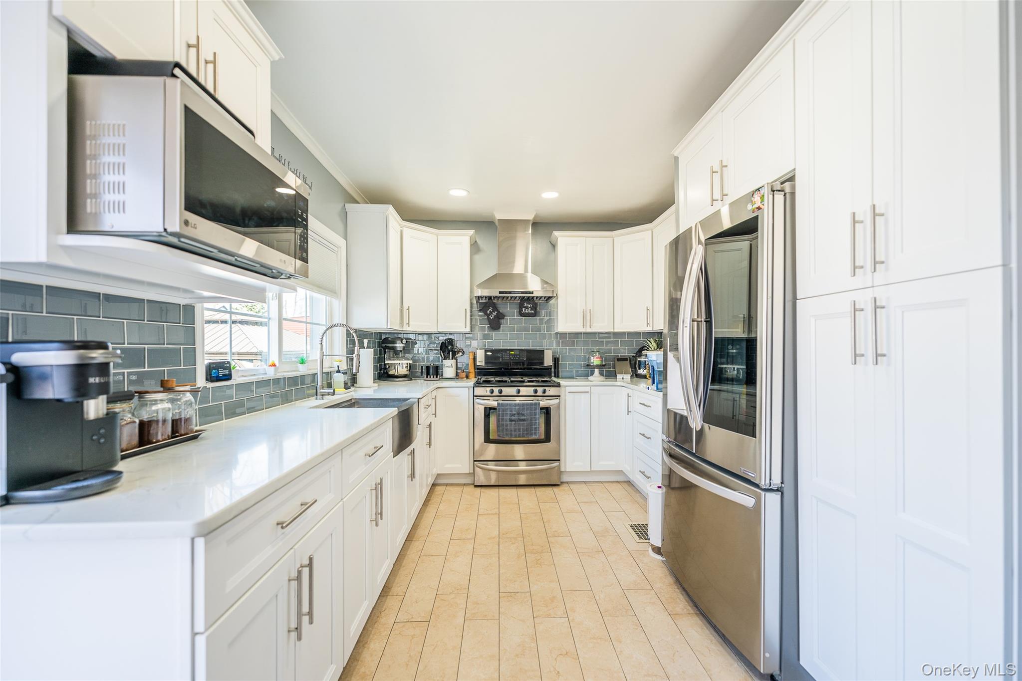 89-32 90th Street Queens, NY 11421 - Photo 2 of 33 Kitchen featuring stainless steel appliances, white cabinets, light stone countertops, light wood-style floors, and tasteful backsplash