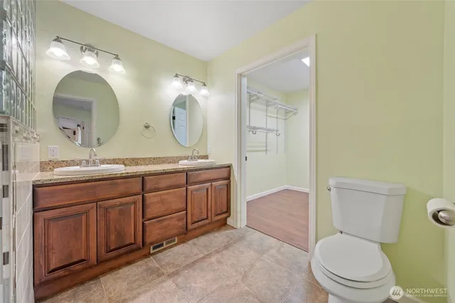 a spacious bathroom with a granite countertop toilet a sink and a mirror