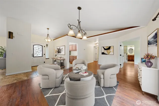 a dining room with wooden floor a chandelier a glass table and chairs