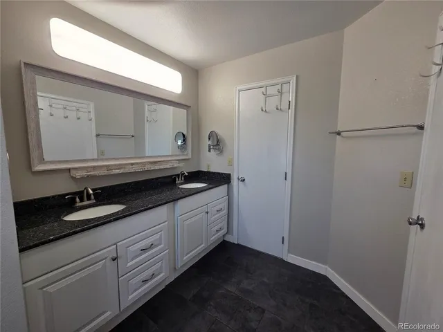 a spacious bathroom with a granite countertop sink and a mirror