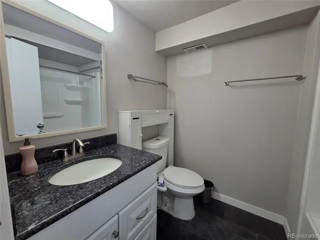 a bathroom with a granite countertop sink toilet and a mirror